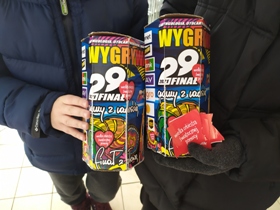 Zdjęcie przedstawia puszki Wielkiej Orkiestry Świątecznej Pomocy trzymane w dłoniach przez wolontariuszy